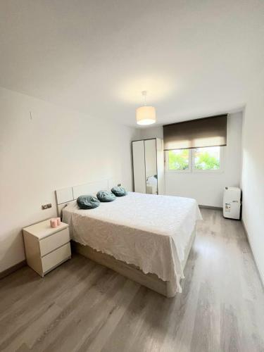 a white bedroom with a large bed and a window at Huerta Nueva Suites in Estepona