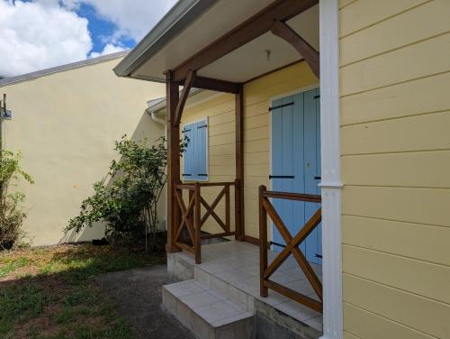 a porch with blue doors on a yellow house at L'Etoile Velli in Salazie