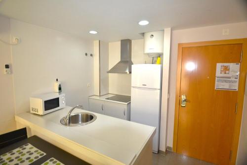 a kitchen with a sink and a white refrigerator at Apartamentos Marina Suites in Grao de Castellón