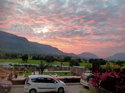 a white car parked in a parking lot with a sunset at Mountain Shadow Resort in Igatpuri