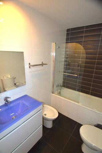 a bathroom with a blue sink and a toilet at Apartamentos Marina Suites in Grao de Castellón