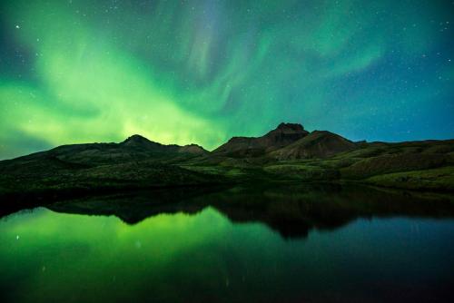 a view of the northern lights over a body of water at Álfheimar Hotel in Borgarfjordur Eystri
