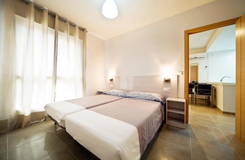 a bedroom with a large white bed and a bathroom at Apartamentos Marina Suites in Grao de Castellón