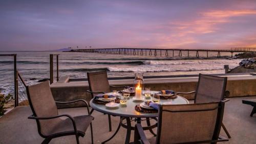 a table with a candle on a balcony with a pier at Seascape by Paradise Retreats in Carpinteria