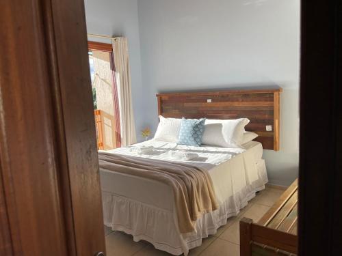 a bed with a wooden headboard in a bedroom at Pousada Rosamar in Praia do Rosa