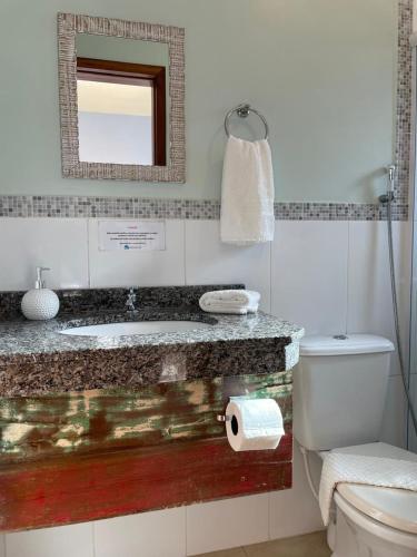 a bathroom with a sink and a toilet and a mirror at Pousada Rosamar in Praia do Rosa