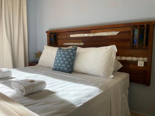 a large white bed with a wooden headboard and pillows at Pousada Rosamar in Praia do Rosa