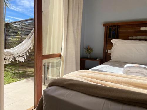 a bedroom with a bed and a sliding glass door at Pousada Rosamar in Praia do Rosa