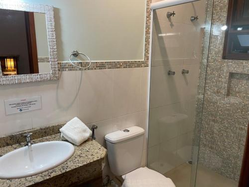 a bathroom with a toilet and a sink and a shower at Pousada Rosamar in Praia do Rosa