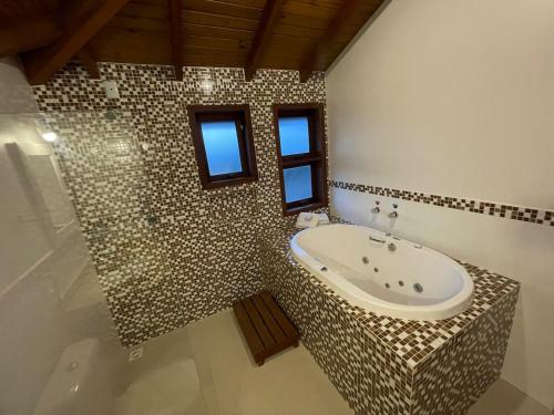 a bathroom with a bath tub and a shower at Pousada Rosamar in Praia do Rosa