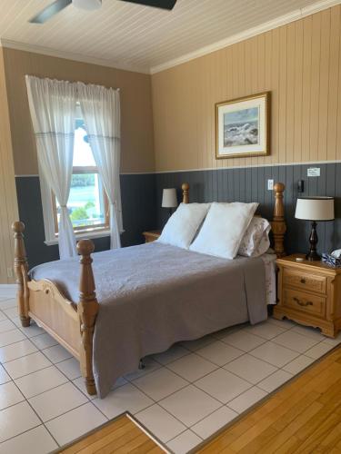 a bedroom with a large bed and a window at Le Manoir du Vieux Presbytère in Port-Daniel