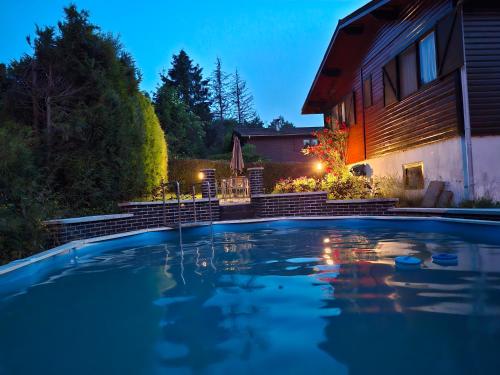 a swimming pool in front of a house at night at Le Belle Homme in Gouvy