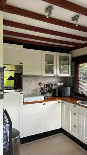 a kitchen with white cabinets and a striped ceiling at Le Belle Homme in Gouvy