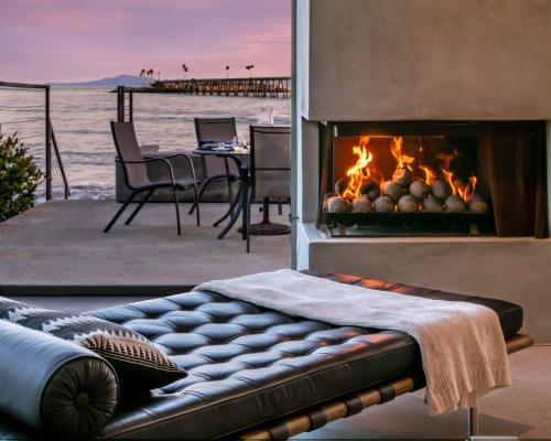 a fireplace with a couch in front of it with a table at Seascape by Paradise Retreats in Carpinteria