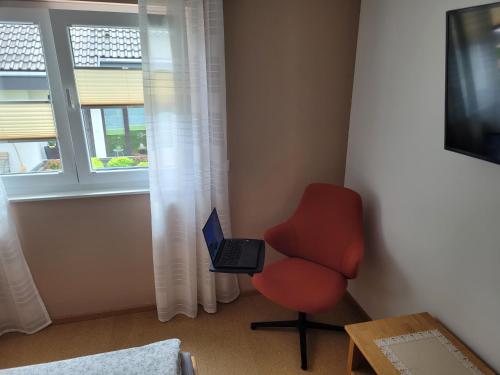 a room with a red chair and a laptop computer at Ferienwohnung Albliebe in Meßstetten