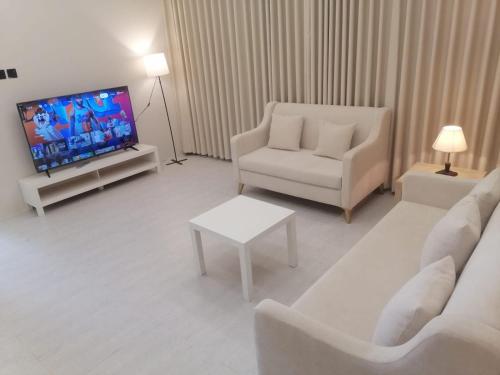 a living room with white furniture and a flat screen tv at شقة 3 احد رفيدة حي الخليج in Ahad Rafidah