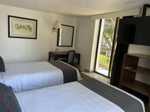 a hotel room with two beds and a flat screen tv at Hotel Del Portal, Puebla in Puebla