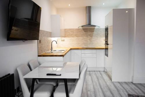 a kitchen with a table and chairs and a sink at Academy Apartments By Elegance Stays in Hull