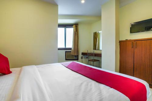 a bedroom with a bed with a red and white blanket on it at Hotel O Pariwar Inn in Hyderabad