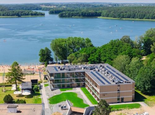 an aerial view of a building with a lake in the background at Omega Lake Prestige # 5 Private Pool & Jacuzzi & Sauna & Gym & Lake Access in Olsztyn