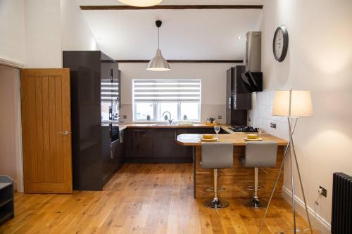 a kitchen with a table and two bar stools at Academy Apartments By Elegance Stays in Hull