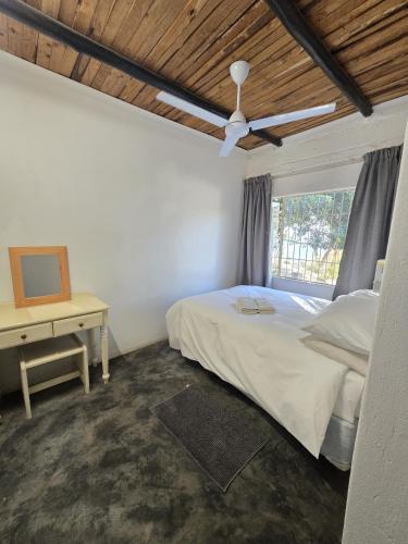 a bedroom with a bed and a desk and a window at Kanaan Guest Farm in Hazyview