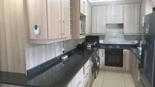 a kitchen with white cabinets and black counter tops at Caribbean Estates Montego bay 30 in Port Edward