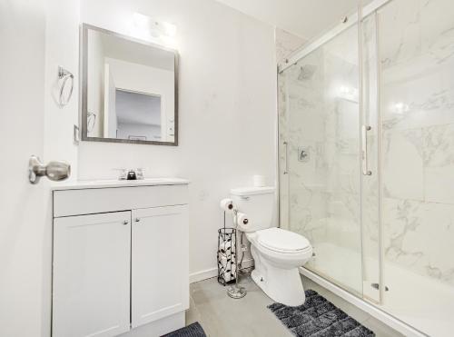 a white bathroom with a toilet and a shower at Superbe 2 chambres à Griffintown in Montréal