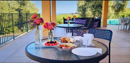 Una mesa de cristal con comida y flores en un patio. en Ortona Holiday B&B, en Ortona