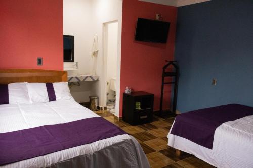 a bedroom with two beds and a tv on the wall at Hotel Boutique Tonalli in San Martín de las Pirámides