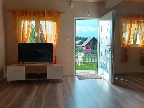 a living room with a tv and a sliding glass door at Mona apartman in Žabljak