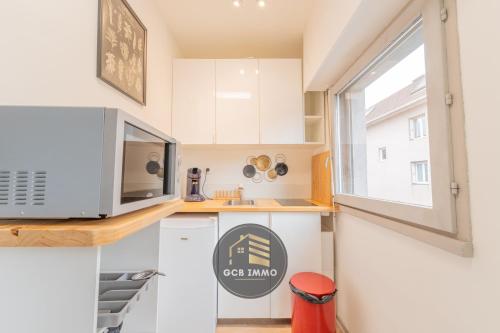 a small kitchen with white cabinets and a microwave at Le REVOL in Grenoble