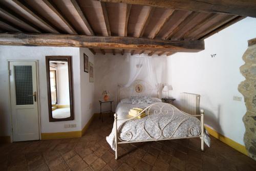 a bedroom with a white bed with a wooden ceiling at Agriturismo La Colombella in Bagni San Filippo