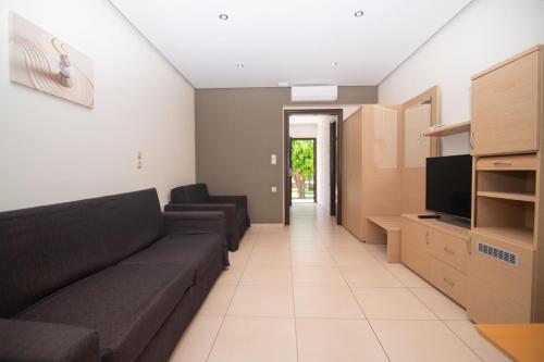 a living room with a couch and a tv at Riviera Perdika Hotel in Perdika