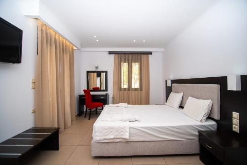 a bedroom with a bed and a desk with a red chair at Riviera Perdika Hotel in Perdika