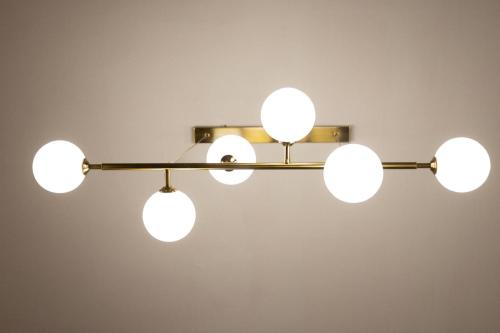a chandelier with five white lights hanging from a wall at My Home in Barletta
