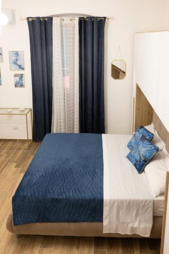a bedroom with a blue and white bed and a window at My Home in Barletta