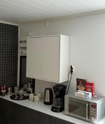 a kitchen with a white cabinet above a microwave at Guest house in Lyckeby in Karlskrona