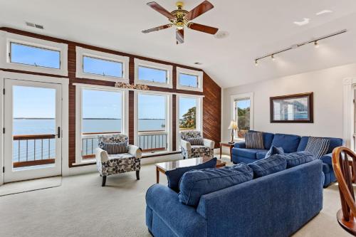 a living room with blue couches and a ceiling fan at 5550 - Lighthouse Pointe in Kill Devil Hills