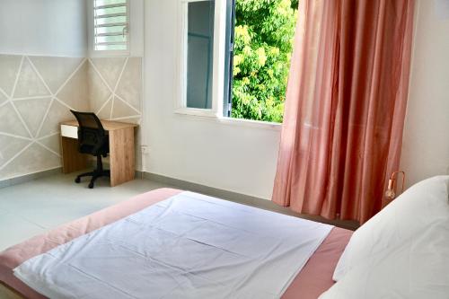 a bedroom with a bed and a window and a desk at Galhy's House in Saint-Claude
