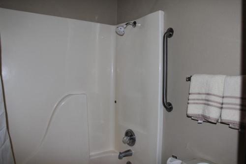 a white bathroom with a shower and a towel at Lodge USA Motel in Guymon