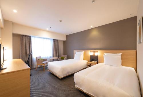 a hotel room with two beds and a desk at ANA Crowne Plaza Hiroshima by IHG in Hiroshima