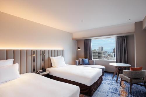 a hotel room with two beds and a window at ANA Crowne Plaza Hiroshima by IHG in Hiroshima