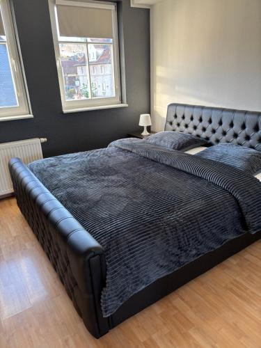 een groot zwart bed in een slaapkamer met twee ramen bij Deutsches Haus in Willingen