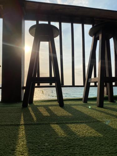 two wooden stools sitting on the beach with the sunset at Brisas del Mar vista al Mar in Playa Blanca
