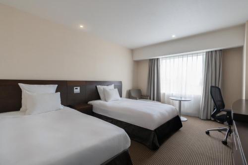 a hotel room with two beds and a window at ANA Crowne Plaza Hiroshima by IHG in Hiroshima