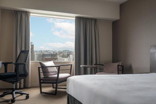 a hotel room with a bed and a large window at ANA Crowne Plaza Hiroshima by IHG in Hiroshima
