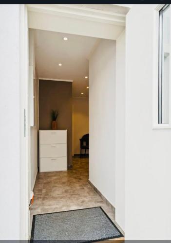 a hallway with white walls and a white dresser at Apartment in Narvik