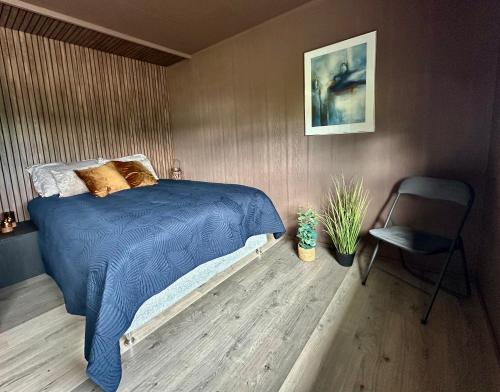 a bedroom with a blue bed and a chair at Senja Beach Lodge in Senja