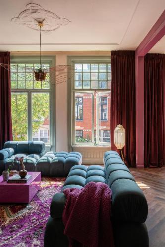a living room with blue couches in a room with windows at Luxurious boutique apartment near city centre in Groningen